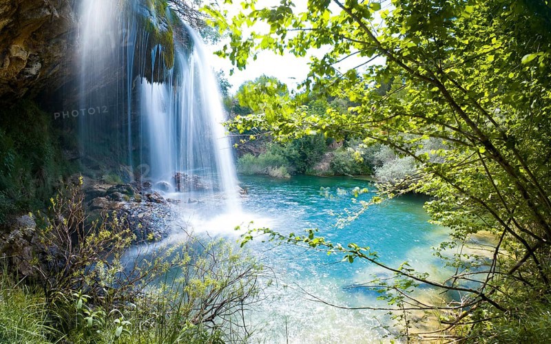 A serene waterfall surrounded by lush greenery pouring into a turquoise pool of water