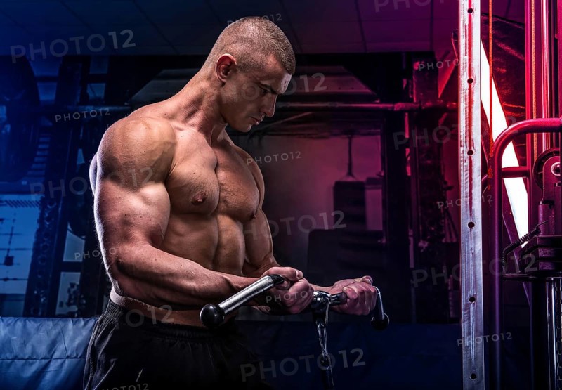 Young bodybuilder training in a gym, lifting hard weigh
