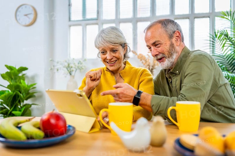 Happy caucasian senior couple shopping online using tablet at home
