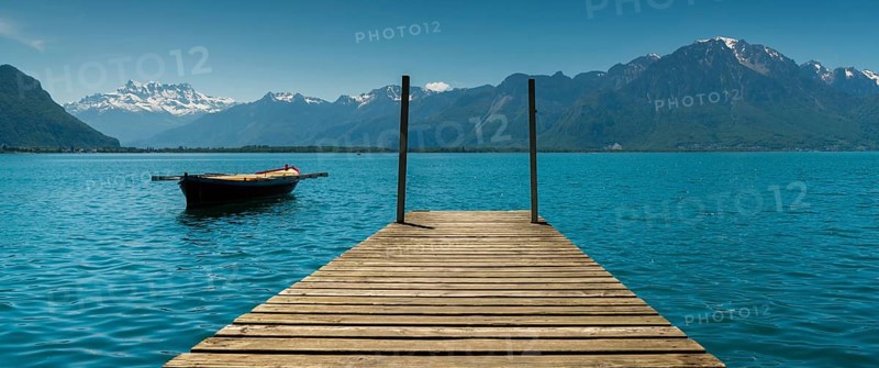 Switzerland - 31 May 2019: mountain and lake landscape with a vintage rescue rowboat and a wooden pier