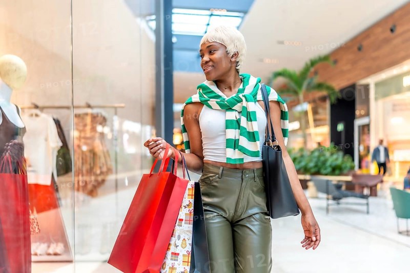 African woman strolling and looking at a shop window in a shopping mall