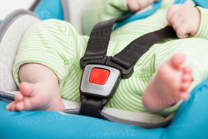 Little baby child fastened with security belt in safety car seat