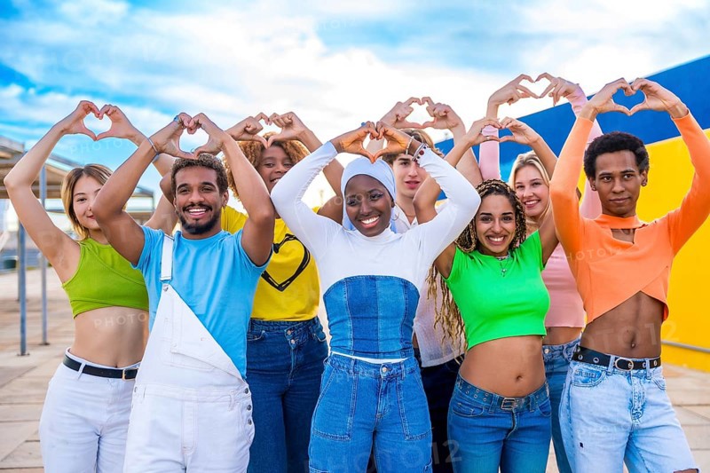 Multi-ethnic young people standing gesturing heart shape with hands outdoors in a urban space