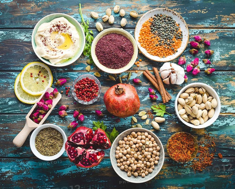 Arab ingredients for middle eastern food. Arabic cuisine ingredients on blue wooden background. Hummus, chickpea, lentils, rose buds, spices, pomegranate, pistachios. Halal food making. Top view