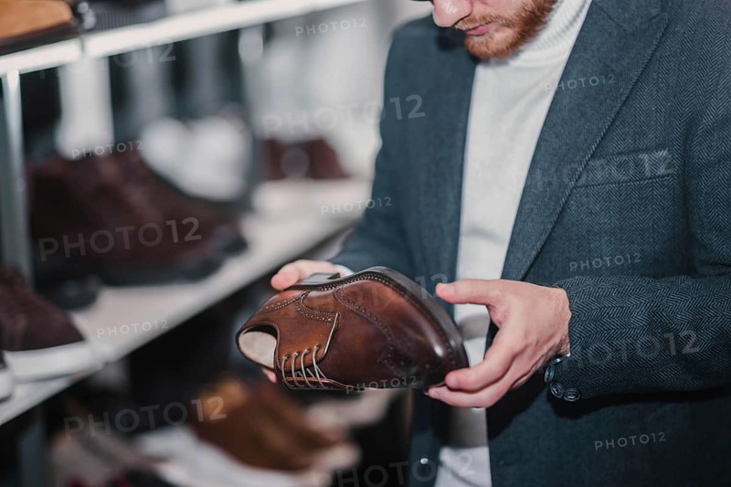 Man in business clothes chooses brown dress shoes in a store