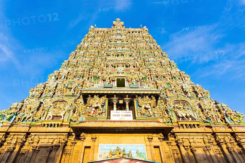 Centered west tower gateway of Meenakshi Amman Temple covered in colorful statues of gods on a blue sky day at Madurai in south Indian state of Tamil Nadu, India, Asia