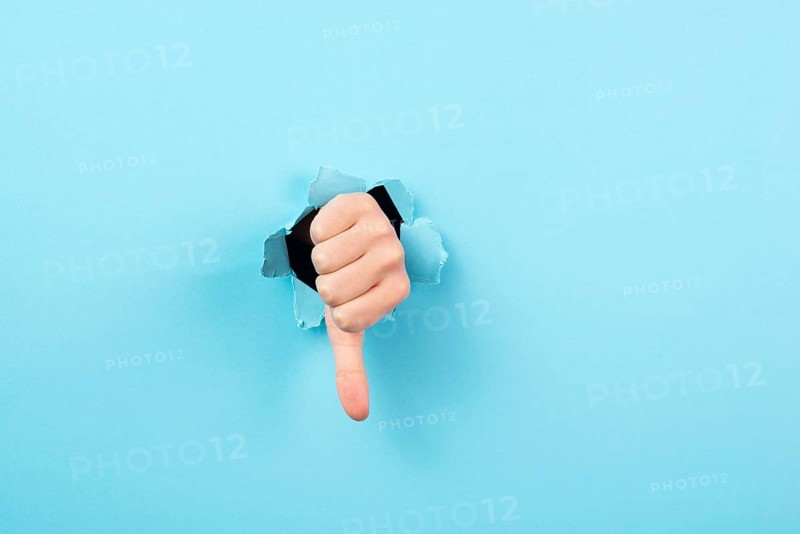 Thumb down, negative hand gesture, dislike or disagree, expression of disappointment, blue torn paper