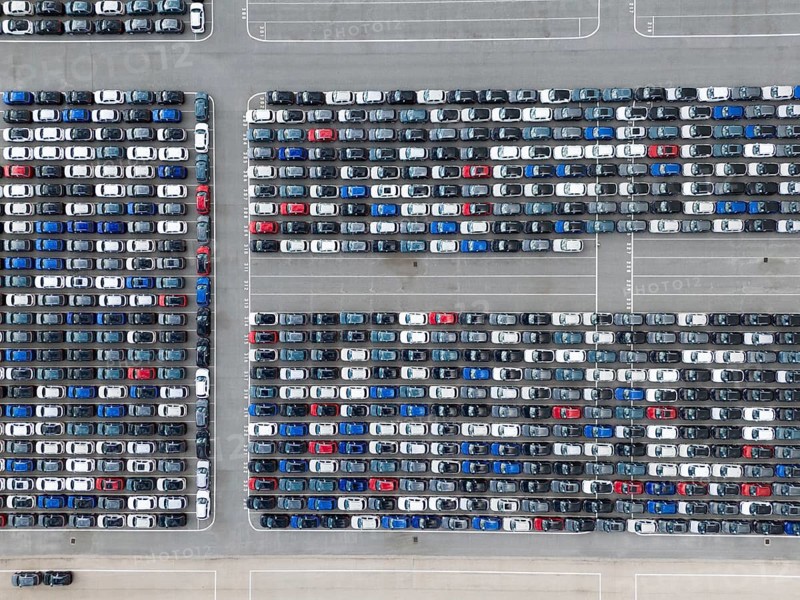 New Cars on Large Parking Lot in Port Ready for Distribution. Harbor Vehicle Storage for Shipping. Automotive Industry. Setubal, Portugal. Aerial Overhead Top-Down Drone Shot.