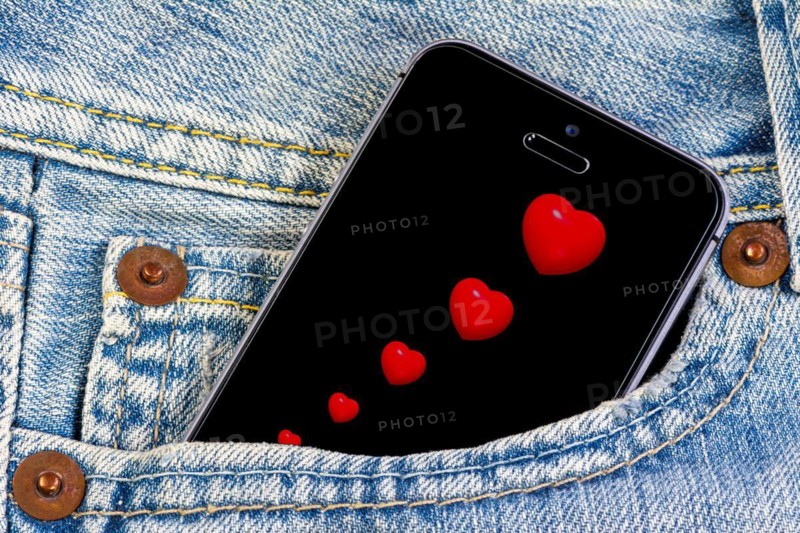 Smartphone with red hearts on the screen in a jeans pocket