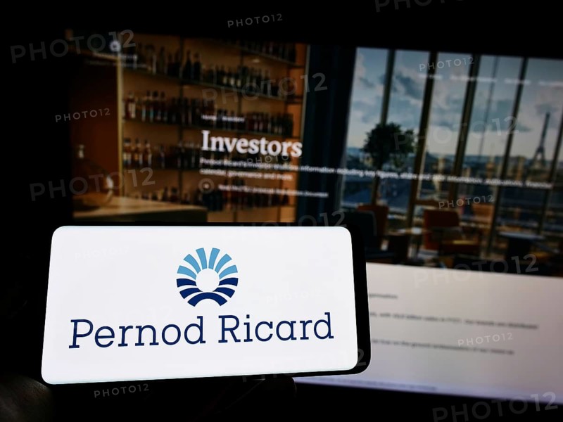 Stuttgart, Germany, 10-14-2022: Person holding mobile phone with logo of French beverage company Pernod Ricard S.A. on screen in front of web page. Focus on phone display, Europe