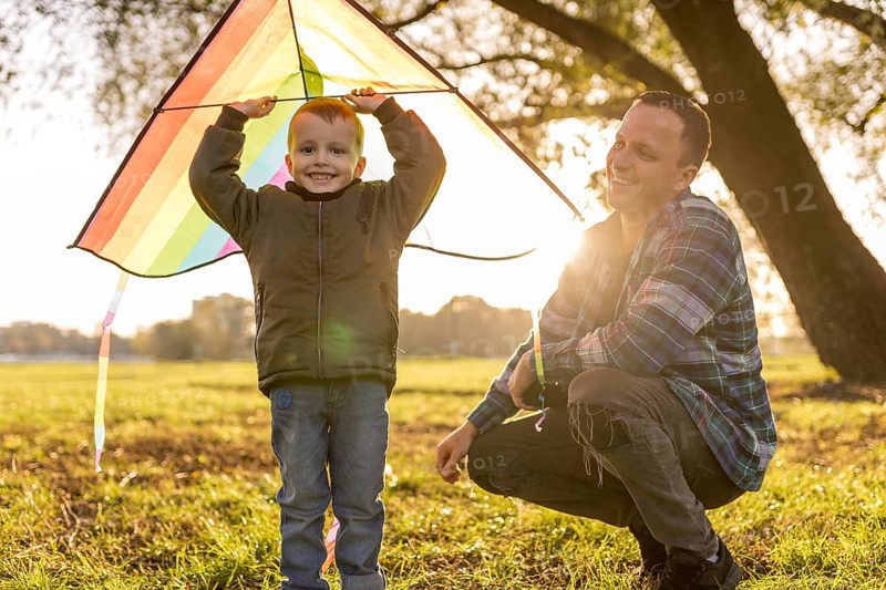 Father son playing together with colourful kite