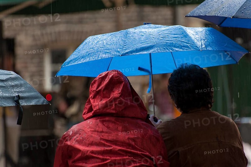 2 people sitting next to each other under umbrellas