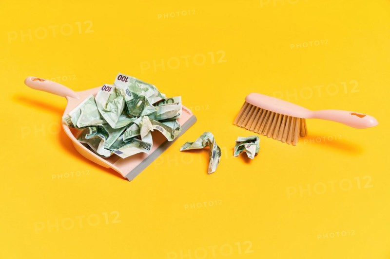 Creative layout with dustpan, hand brooms and crumpled money dollar bills on yellow background. Finance, corruption, criminal activity concept