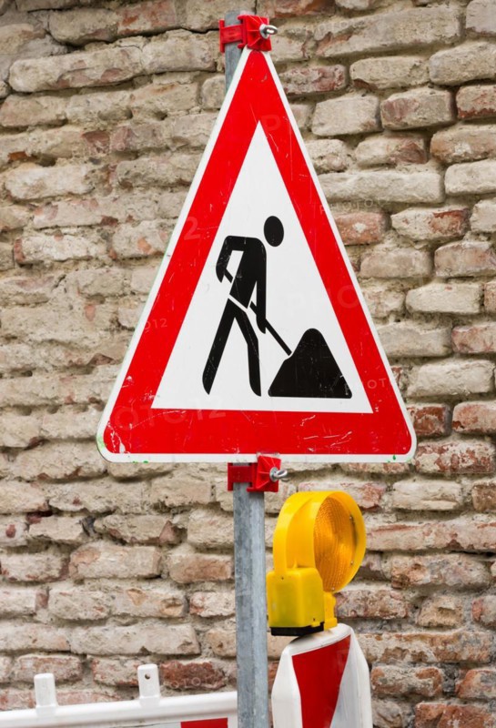 Traffic sign at a construction site with a brickwall in the background