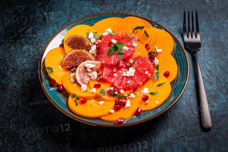 Healthy winter salad - Persimmon carpaccio salad with pomegranate, feta cheese, pink grapefruit and figs