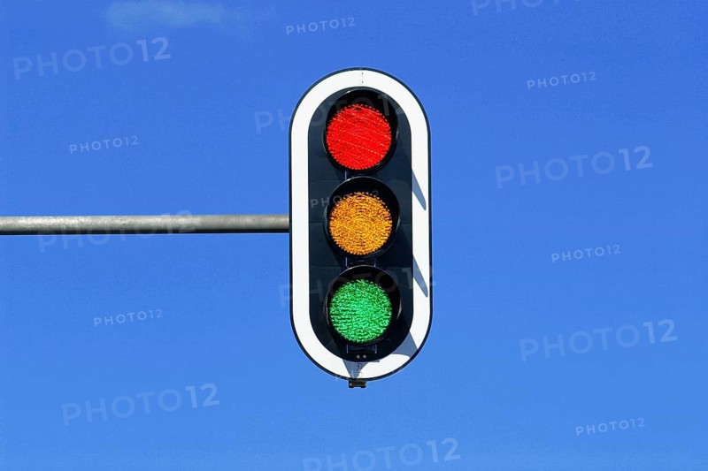 Traffic light in blue sky with red, yellow and green lights on at the same time, blue sky as background