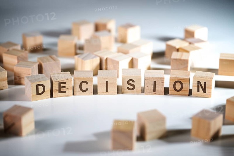 Word DECISION written on wooden cubes among a lot of others, concept to make the right choice in business and job, gray background, copy space, selected focus, narrow depth of field