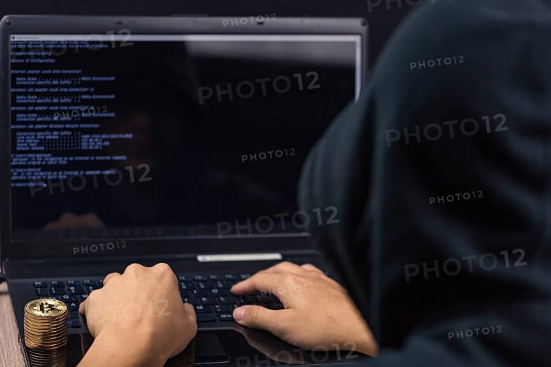 Dangerous hooded hacker on laptop breaks computer security sistem and steal bitcoin cryptocurrency