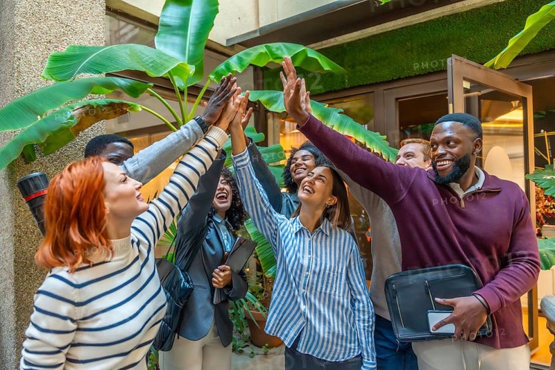 Diverse happy coworkers with hand put together for the unit of teamwork in a nice patio of a coworking space