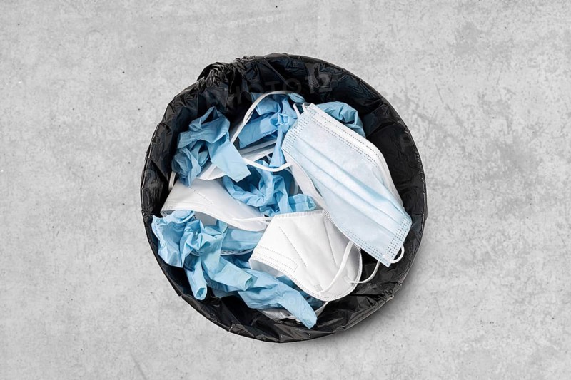 Trash can full of used face mask and protective gloves. Covid-19 protective wear waste concept. Top view