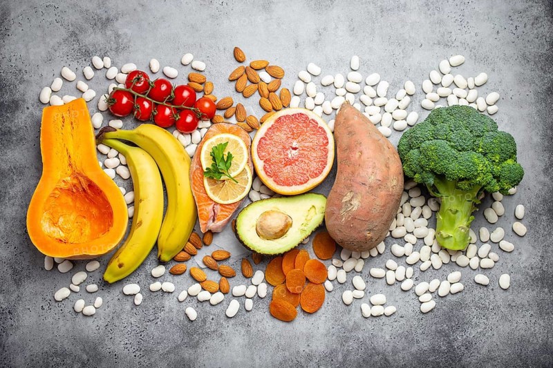 Vegetables, fruit and foods containing potassium over gray stone background, top view. Natural sources of potassium, vitamins and micronutrients for healthy balanced diet and avitaminosis prevention