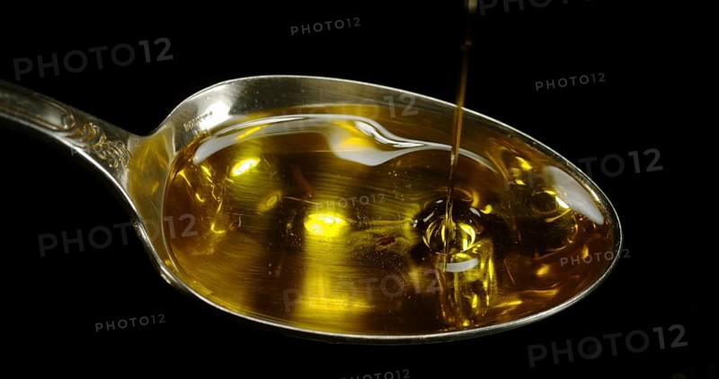 Olive Oil, Falling in a Spoon against Black Background