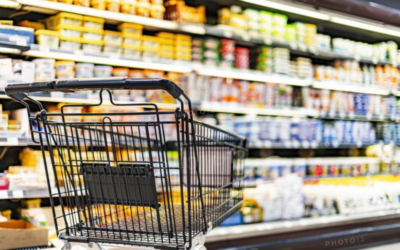 A shopping cart by a store shelf in a supermarket