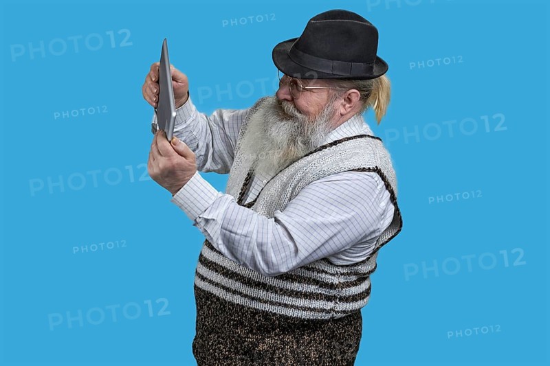 Portrait of excited senior man playing video game on tablet pc. Isolated on blue