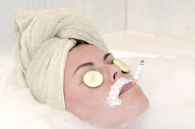 Headshot on a Woman Relaxing in the Bathtub with a Towel on Her Head and Smoking a Cigarette in a SPA in Switzerland