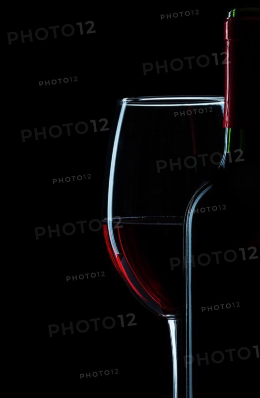 Bottle and wine glass with red wine close-up on white background
