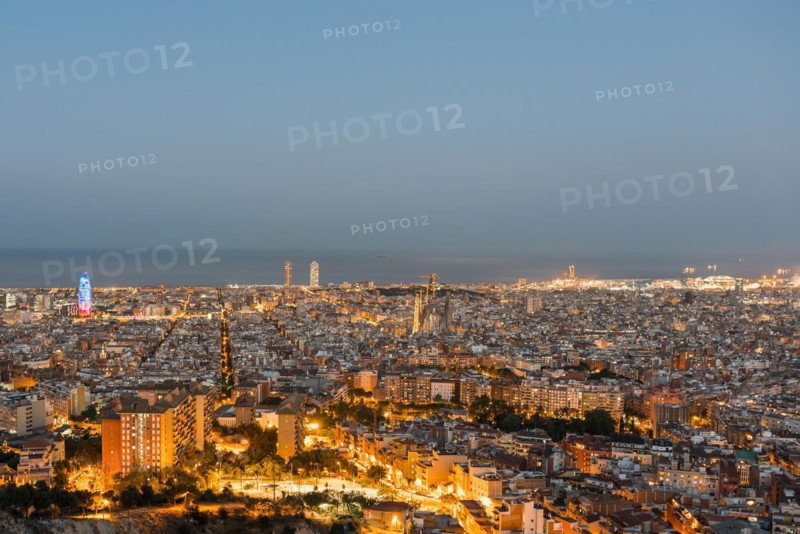 Top view and night photography from an illuminated Barcelona. The panorama shows the famous Sagrada Familia, the illuminated Torre Agbar and the Towers of the Port Olimpic until the harbor