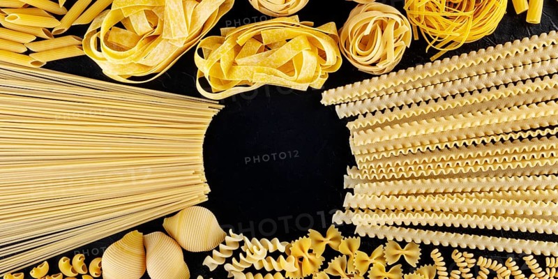 Italian pasta panoramic design with copyspace, a flatlay of an assortment of pasta types, shot from the top on a black background with a place for text