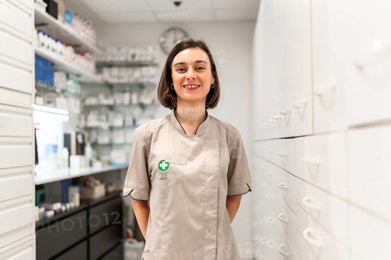 Portrait of a young woman pharmacist standing in the storage room smiling at camera