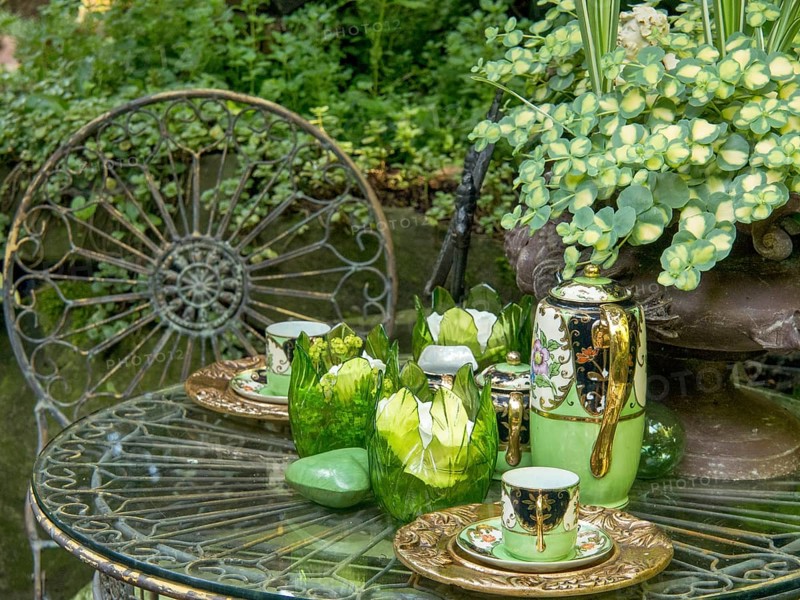 A decorated garden table with green tea service, glasses and plants in the background, borken, westphalia, germany