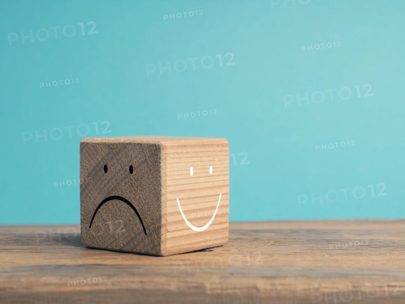 A wooden cube with light and dark side, once with smiling face and with sad face, There is always the option to choose, which face do you choose?