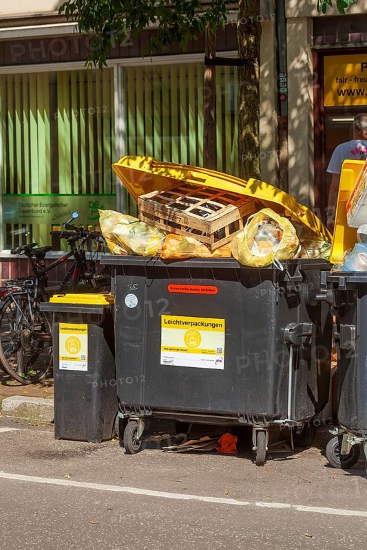 Overfilled waste containers for lightweight packaging standing on the street, Germany, Europe