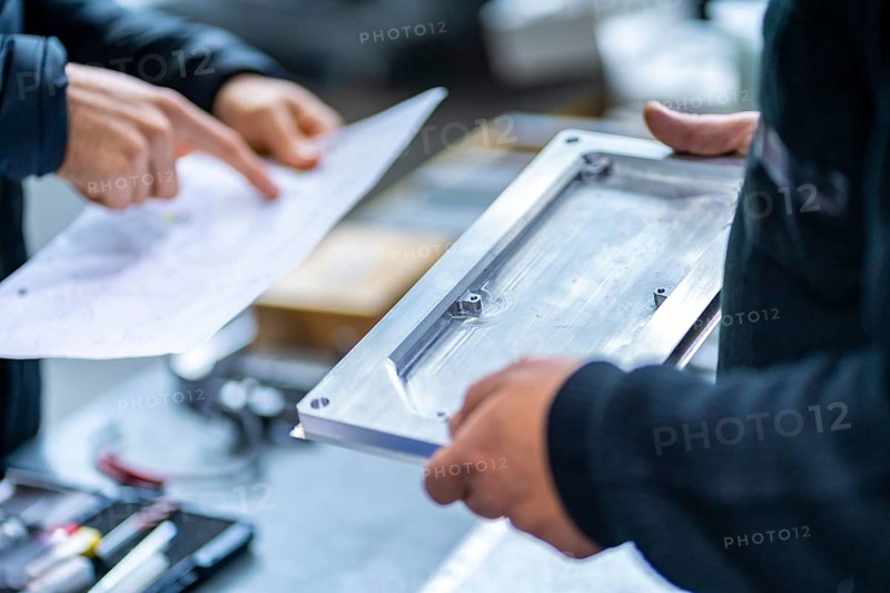 Close-up of engineers working on cnc factory examining pieces