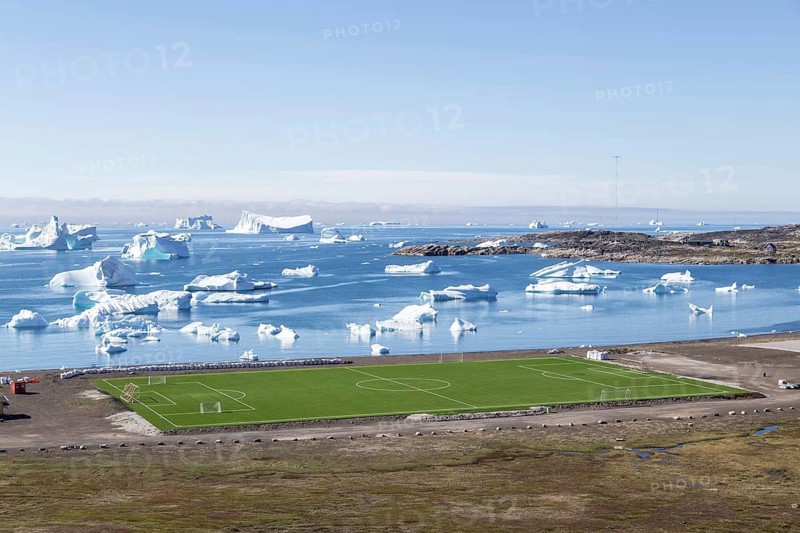 Qeqertarsuaq, Greenland, July 6, 2018: The local soccer field with icebergs in the background, North America