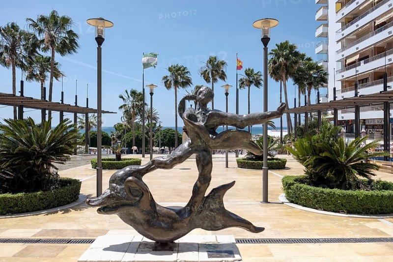 Man Above Dolphin Statue by Salvador Dali in Marbella
