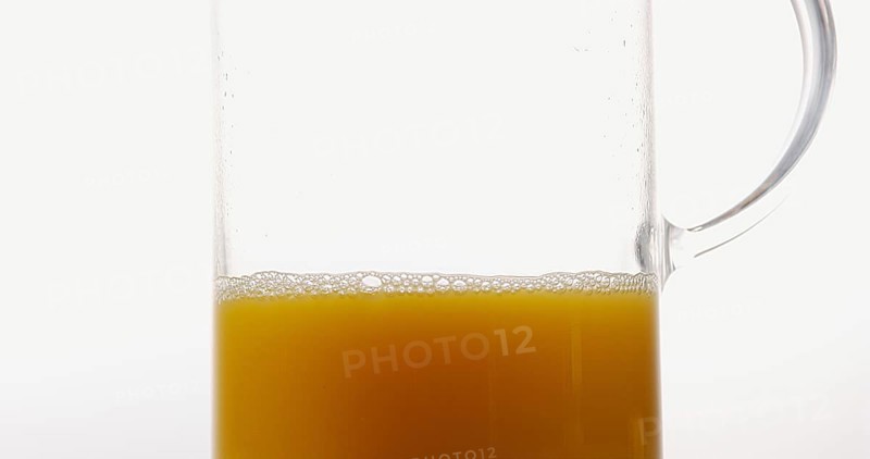Orange Juice being poured into Glass against White Background