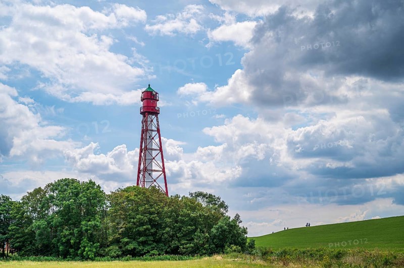 Red lighthouse with metal scaffolding stands next to a green field under a cloudy sky, lighthouse Campen, Hamswehrum, Krummhörn, East Frisia, Lower Saxony