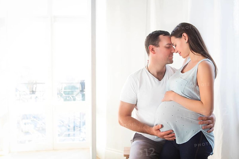 Pregnant woman and young man together indoors