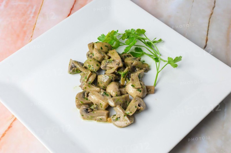 Herb-marinated mushrooms with parsley on a square white plate, typical food, typical mediterranean mallorcan cuisine typical from balearic islands mallorca, spain