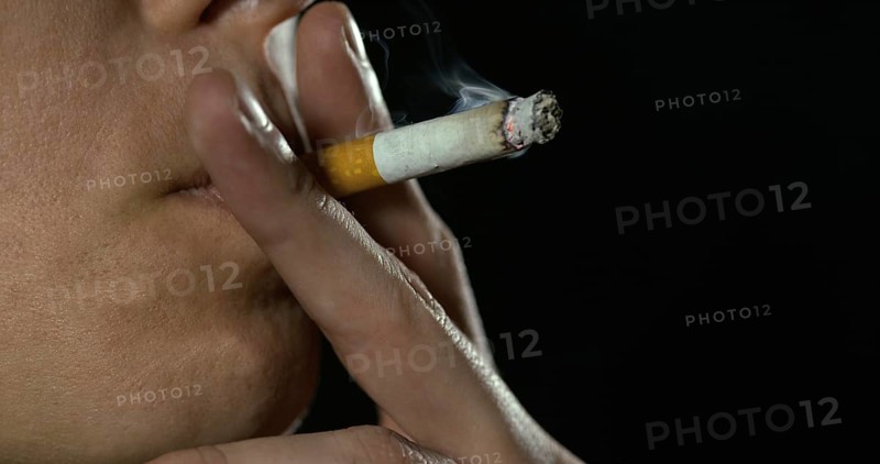 Woman smoking a Cigarette against Black Background