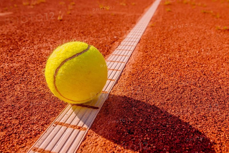Yellow tennisball on the line at a clay court