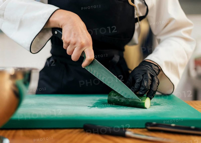 Front view female chef slicing cucumber