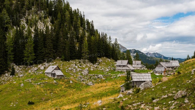 Log cabins in the mountains of the Slovenian Alps on the peak Planina Blato on sunny day with clouds