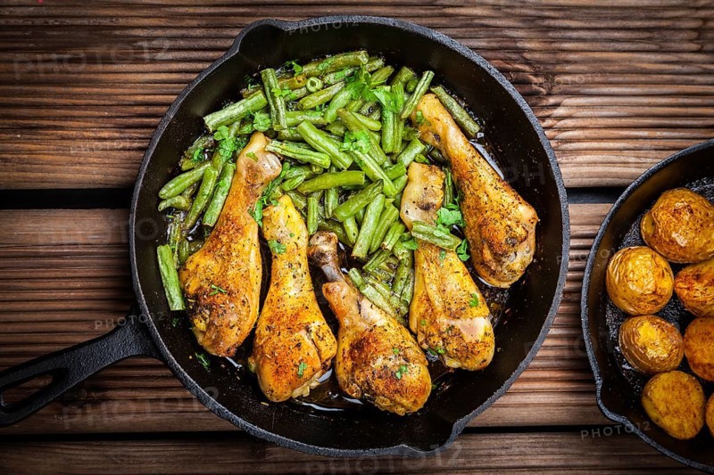 Chicken legs in pan with potatoes, green beans and salad