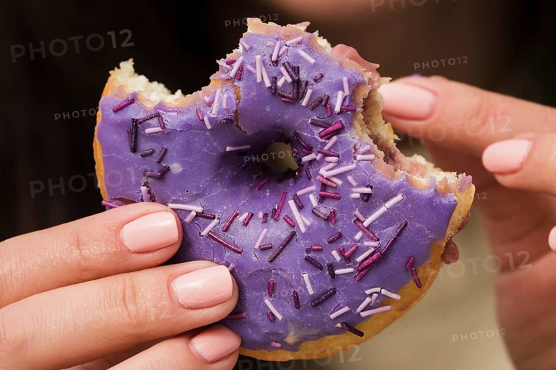 Close up woman eating purple donut