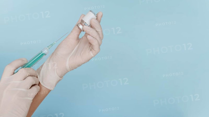 Hand with gloves holding syringe with vaccine copy space